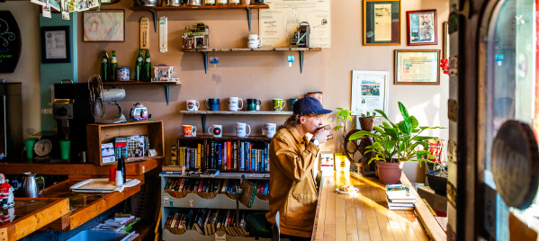side view of a person sitting at a window drinking a cup of coffee at Sprocket Cafe