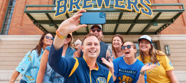 A group of Brewers fans smile in front of American Family Field