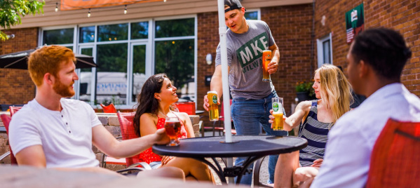 friends gathered around table outside of Black Husky Beer