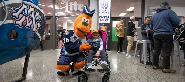 The Milwaukee Admirals mascot, Roscoe, with a young fan in a wheelchair.