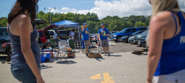 A group of Brewers fans playing a game of corn hole while they tailgate