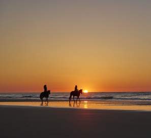 Horseback riding on the beach at sunset in the Golden Isles