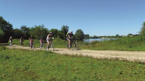 A group of people cycle alongside a lake
