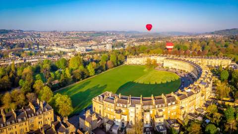 Two red hot air balloons float above the Royal Crescent, a row of 30 terraced houses laid out in a sweeping crescent, in the centre of Bath