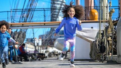 Photograph showing two young children running along the main deck of HMS Warrior at Portsmouth Historic Dockyard