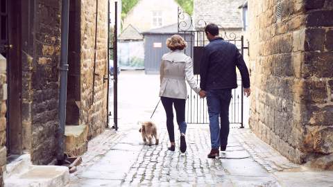 A couple walking a dog outside the Lygon Arms Hotel