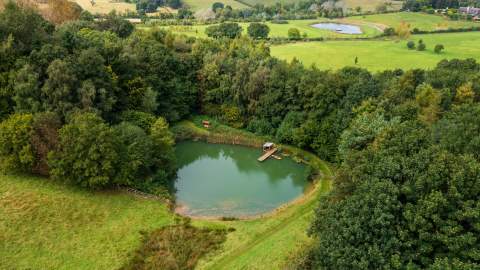 The spring-fed lake at Heath Farm Holiday Cottages surrounded by woodland and open fields