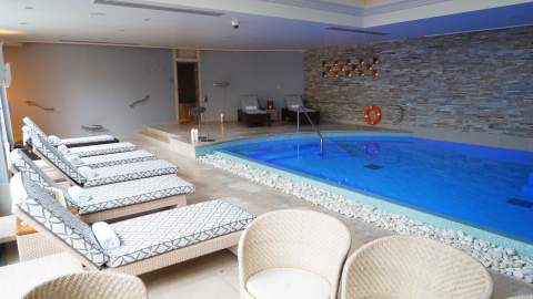 Padded sunbeds sit alongside an indoor pool at Cotswold House Hotel & Spa in the Cotswolds