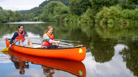 A couple in a bright orange canoe paddle down the rive at Ross on Wye in the Forest Of Dean & Wye Valley