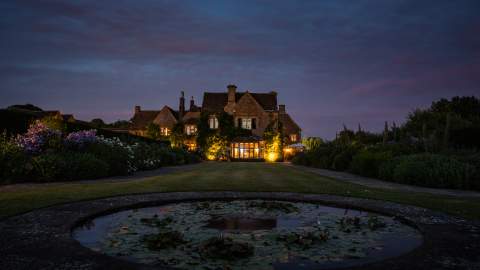 Lights glow from Whatley Manor as dusk sets in
