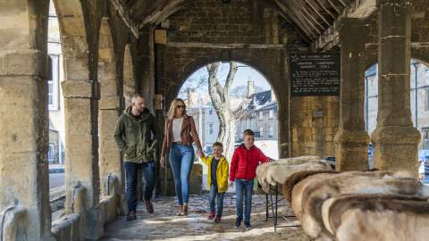 Family with Mother, Father and children walking though Woolmarket House in Chipping Campden. Furs for sale in foreground