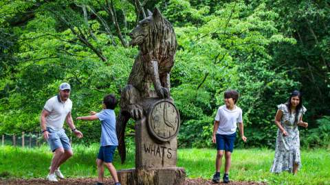 Family playing around wooden statue at Westonbirt Arboretum