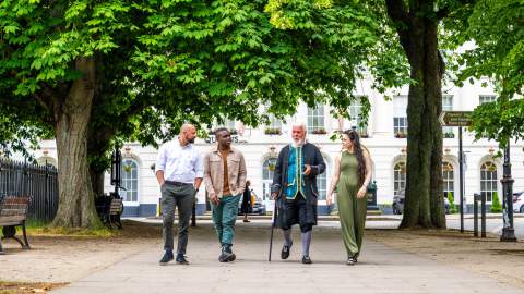 A group of people on a walking tour with a costumed guide in Cheltenham