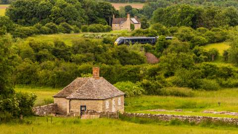 A view of North Leigh Roman Villa with a GWR train passing in the distance behind