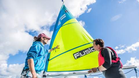 two men in front of a sailing boat