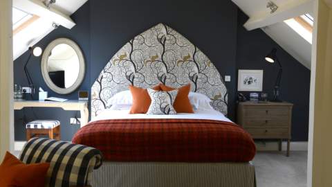 Bedroom at The Close Hotel in Tetbury with dark blue wall and elaborate headboard