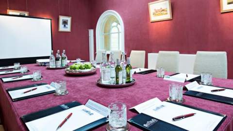 A meeting room with burgundy walls and modern equipment at Blenheim Palace in the Cotswolds