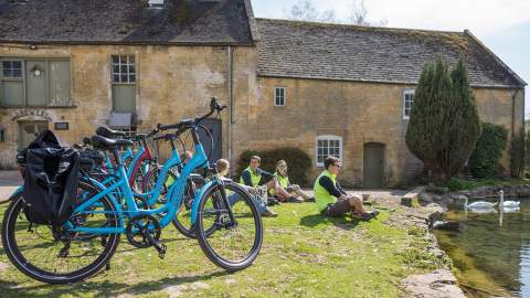 A group of cyclists sitting by a pond
