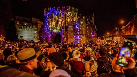 Crowd watching Christmas Market light projection show on bargate
