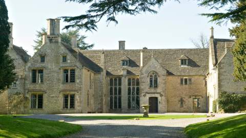 The front of Chavenage House, a Cotswold stone manor house surrounded by trees