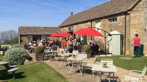 People dining outside in the sunshine at Morris & Brown Café at Broadway Tower in the Cotswolds