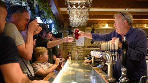 Jeremy Clarkson passes a pint to a customer at his busy bar at The Farmer's Dog