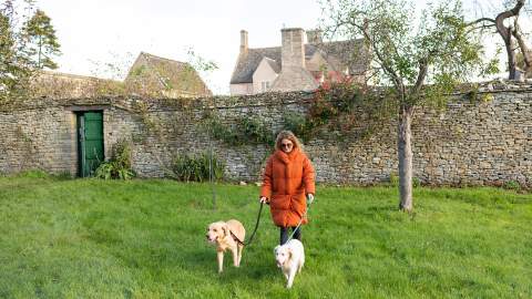 Woman with two dogs walking through the orchard at Cogges Manor Farm