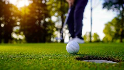 Golfball foran et hull på golfbanen