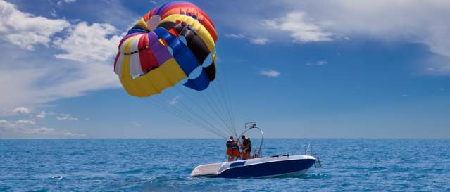 A small boat with a colorful parachute in tow.