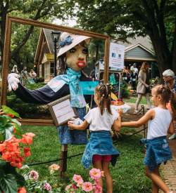 Little girls on an outdoor pathway at Peddler's Village in Lahaska, PA standing in front of a unique scarecrow