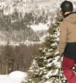 Person in snow gear on a snowboard at the top of a mountain covered in snow