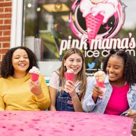Three kids happily eat their pink ice cream cones at Pink Mama's Ice Cream in Travelers Rest, SC.