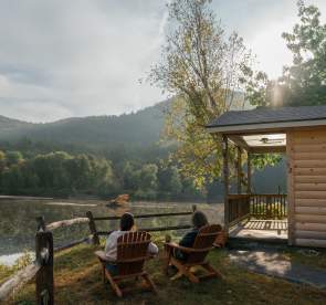 Women sitting in Adirondack chairs in front of the Hudson River at 1000 Acres Ranch