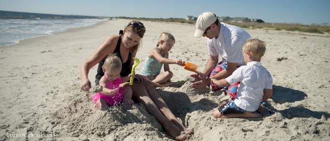 Family building sandcastles on Caswell Beach, NC.