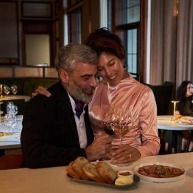 Couple holding each other. Wine in hand and small bites around them.