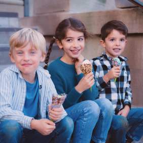 Three children sitting on a staircase eating ice cream