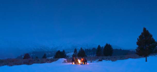 Group of people gathered around a campfire during winter.