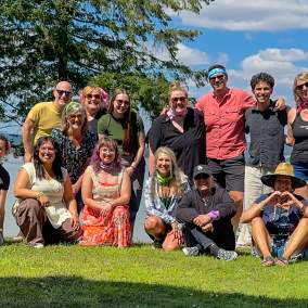 A portion of the staff for Travel Lane County on the grass by Fern Ridge during a team retreat.