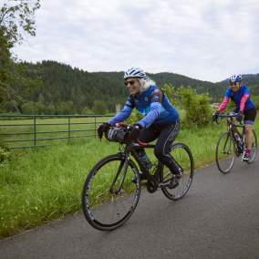 Three people riding single file along a country road.