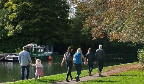 People walking along the Thames Path along the river.