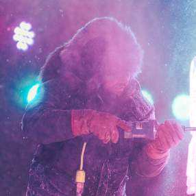 An ice carver using a power tool to carve a sculpture during the Freezefest ice battle