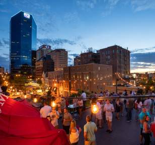 Roof top bar, Belle, filled with patrons enjoying drinks as the sun goes down behind the city skyline.