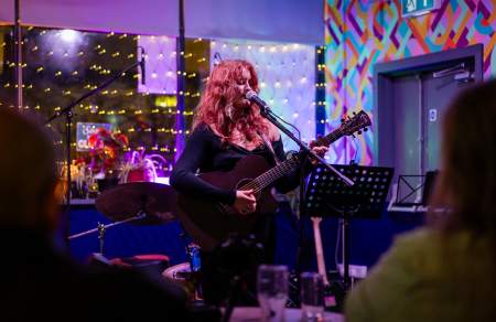 A woman playing an acoustic guitar on a small stage
