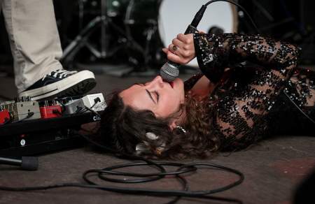 A woman lying on the ground singing into a microphone