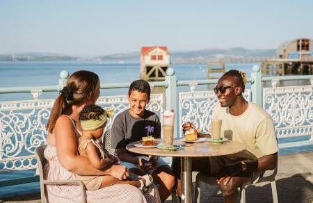 A family enjoying food outdoors on Mumbles Pier.