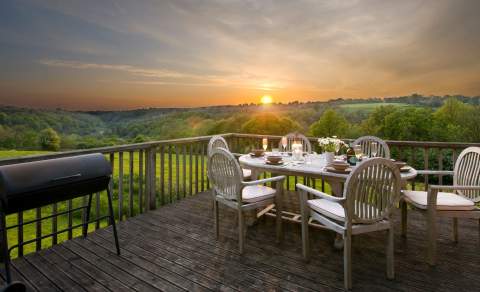 Landscape shot of sunset from the deck of a glamping tent with a set table and chairs in the foreground