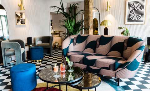 Three cocktails on a table in a stylish cocktail lounge with bold-print sofa and checkered floor at The Old Stocks Inn in the Cotswolds