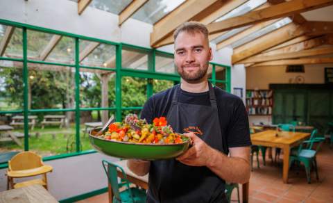 A chef holds a large dish of food in the cafe at The Organic Farm Shop & Cafe, Abbey Home Farm