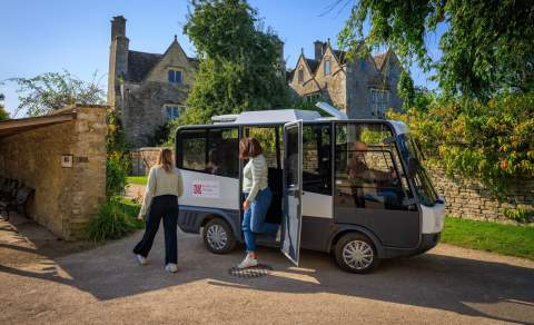 Visitors getting off of an electric shuttle bus at Kelmscott Manor