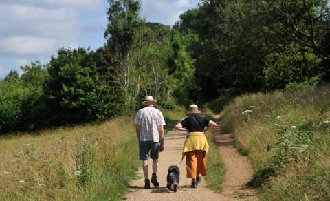 Two people walking their dog on Leckhampton Hill, Cheltenham.